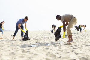 Group Of Volunteers Tidying Up Rubbish On Beach