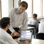 Instructor speaking to a mature student at their desk in a classroom setting